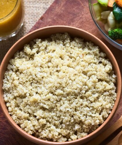 A bowl filled with fluffy, cooked quinoa placed on a wooden surface